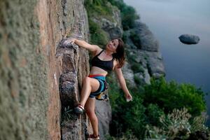 un' ragazza si arrampica un' roccia. donna impegnato nel estremo sport. foto