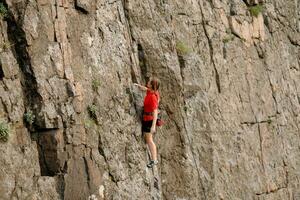 un' ragazza si arrampica un' roccia. donna impegnato nel estremo sport. foto