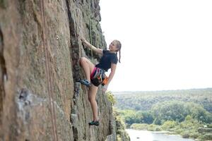 un' ragazza si arrampica un' roccia. donna impegnato nel estremo sport. foto