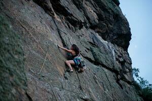 un' ragazza si arrampica un' roccia. donna impegnato nel estremo sport. foto