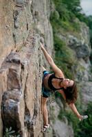 un' ragazza si arrampica un' roccia. donna impegnato nel estremo sport. foto