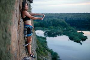 un' ragazza si arrampica un' roccia. donna impegnato nel estremo sport. foto