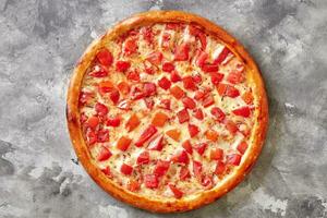rosolato Pizza con succoso pomodori, fuso Mozzarella e italiano erbe aromatiche su grigio pietra superficie foto