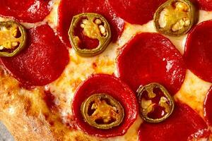 avvicinamento di speziato Pizza con peperoni, pomodoro salsa, Mozzarella e jalapeno foto