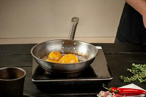 Pesche su un' friggere padella. in scatola frutta giallo Pesche, nero di legno sfondo, tavola. foto