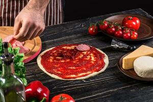 cucinare nel il cucina mettendo il ingredienti su il Pizza. Pizza concetto. produzione e consegna di cibo. foto