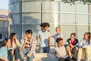 grande gruppo di contento adolescenziale amici parlando nel un' panchina nel il strada di il alunno città universitaria. foto