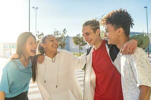 multietnico gruppo di giovane contento amici ridendo nel il strada Tenere ogni altro affettuosamente. foto