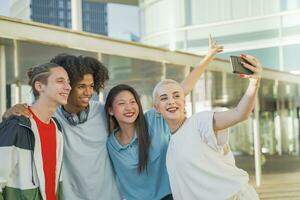 multietnico adolescenziale amici assunzione un' autoscatto gruppo foto e ridendo contento nel il città universitaria