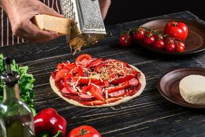 cucinare nel il cucina mettendo il ingredienti su il Pizza. Pizza concetto. produzione e consegna di cibo. foto