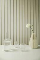 bicchiere vaso con acqua e fiore su bianca tavolo contro di legno parete foto