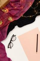nero occhiali, rosa carta con nuovo anni obiettivi. sciarpa e Natale luci su bianca sfondo. foto