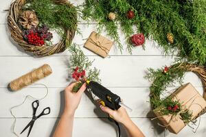 Natale fatto a mano Fai da te sfondo. fabbricazione mestiere natale ghirlanda e ornamenti. superiore Visualizza di bianca di legno tavolo con femmina mani. foto