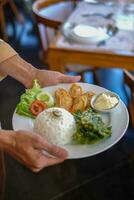 camerieri nel Indonesia trasportare bianca piatti contenente il cibo quello volontà essere servito. il cibo consiste di la verdura, carne e Maionese foto