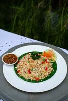 fritte riso con la verdura, pollo e chili salsa è servito su un' bianca piatto su il tavolo foto