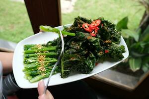 fritte cucinato verde verdure chiamato kailan servito su un' ristorante cenare tavolo utilizzando un' bianca piatto foto