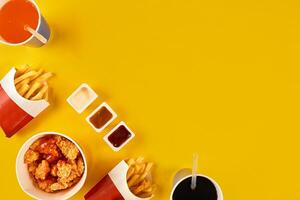 veloce cibo piatto su giallo sfondo. veloce cibo impostato fritte pollo e francese patatine fritte. prendere lontano veloce cibo. foto