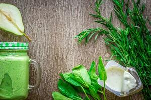 salutare verde frullato con spinaci nel un' boccale contro su di legno sfondo foto