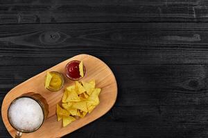 bicchiere di birra con nachos patatine fritte su un' di legno sfondo. foto