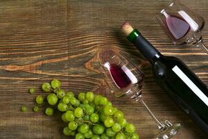 rosso vino bottiglia, uva, cioccolato e bicchieri al di sopra di di legno tavolo. superiore Visualizza con copia spazio foto