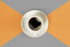 un' tazza di nero caffè su arancia e grigio sfondo. Visualizza a partire dal sopra. foto
