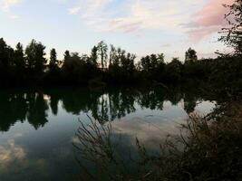 un' lago con alberi e cielo riflessa nel esso foto