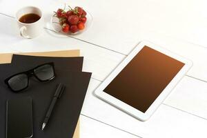 moderno posto di lavoro con digitale tavoletta computer e mobile Telefono, tazza di caffè, penna e vuoto foglio di carta. foto