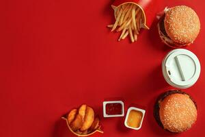 veloce cibo piatto superiore Visualizza. carne hamburger, Patata patatine fritte e bicchiere di bevanda su rosso sfondo. porta via composizione. foto