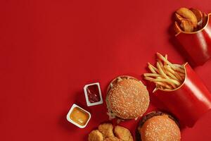 Due hamburger e francese patatine fritte, salse su rosso sfondo. veloce cibo. superiore Visualizza. foto