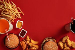 veloce cibo piatto superiore Visualizza. carne hamburger, Patata patatine fritte e bicchiere di bevanda su rosso sfondo. porta via composizione. foto