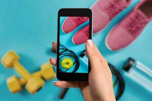 femmina mano con un' smartphone fa un' foto fitness attrezzatura su blu sfondo