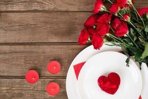 San Valentino giorno cena tavolo ambientazione con rosso nastro, Rose, coltello e forchetta squillare al di sopra di quercia sfondo. foto