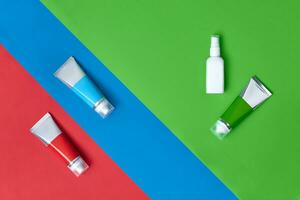 tre cosmetico tubi e bianca pompa bottiglia con no logo su colorato studio sfondo. confezione e pubblicità, il branding la zona. vicino su, copia spazio foto