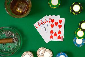 gioco d'azzardo, fortuna e divertimento concetto - vicino su di casinò patatine fritte, Whisky bicchiere, giocando carte e sigaro su verde tavolo superficie foto