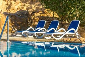 parecchi di sole lettini di bellissimo nuoto piscina e alberi. foto