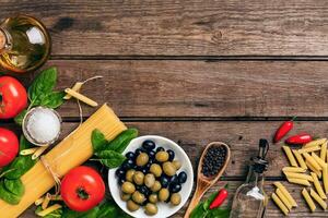 crudo ingredienti per il preparazione di italiano pasta, spaghetti, basilico, pomodori, olive e oliva olio su di legno sfondo. superiore Visualizza. copia spazio. foto