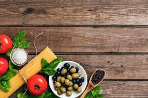 crudo ingredienti per il preparazione di italiano pasta, spaghetti, basilico, pomodori, olive e oliva olio su di legno sfondo. superiore Visualizza. copia spazio. foto