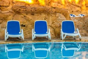 parecchi di sole lettini di un' bellissimo nuoto piscina foto