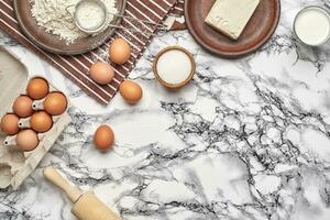 avvicinamento sparo. superiore Visualizza di un' cottura al forno ingredienti e utensili da cucina su il marmo tavolo sfondo. foto
