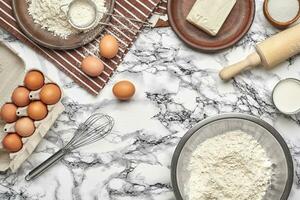 avvicinamento sparo. superiore Visualizza di un' cottura al forno ingredienti e utensili da cucina su il marmo tavolo sfondo. foto