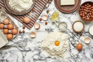 avvicinamento sparo. superiore Visualizza di un' cottura al forno ingredienti e utensili da cucina su il marmo tavolo sfondo. foto