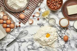 avvicinamento sparo. superiore Visualizza di un' cottura al forno ingredienti e utensili da cucina su il marmo tavolo sfondo. foto