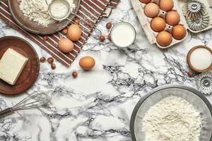 avvicinamento sparo. superiore Visualizza di un' cottura al forno ingredienti e utensili da cucina su il marmo tavolo sfondo. foto