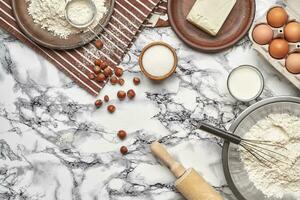 avvicinamento sparo. superiore Visualizza di un' cottura al forno ingredienti e utensili da cucina su il marmo tavolo sfondo. foto