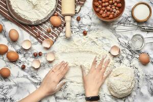 avvicinamento sparo. superiore Visualizza di un' panettiere cucinare posto, mani siamo Lavorando con un' crudo Impasto su il marmo tavolo sfondo. foto