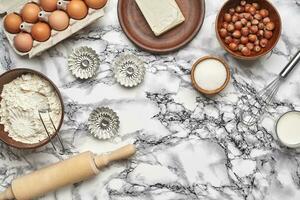 avvicinamento sparo. superiore Visualizza di un' cottura al forno ingredienti e utensili da cucina su il marmo tavolo sfondo. foto