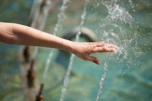 la mano umana raggiunge il getto d'acqua foto