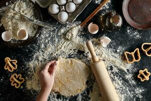 femmina mani rotolamento Impasto con un' rotolamento perno su un' nero tavolo. superiore Visualizza foto