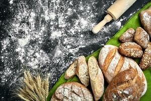 diverso pane con Farina e spighette di grano nero sfondo foto