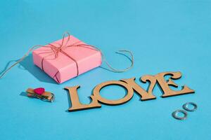 di legno iscrizione amore, regalo scatola e il squillare su blu sfondo. matrimonio proposta. il concetto di San Valentino giorno foto